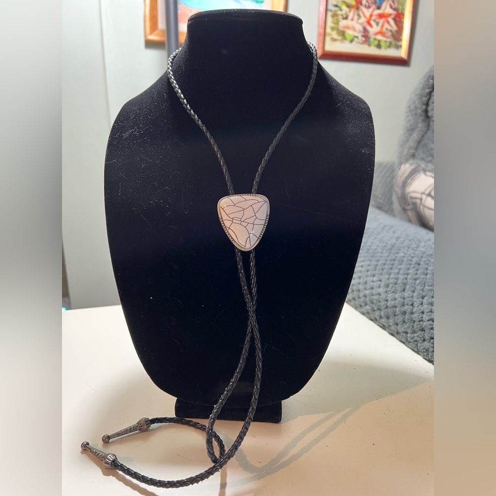 Bolo style neckwear on a black cord with inverted triangle shaped white stone.